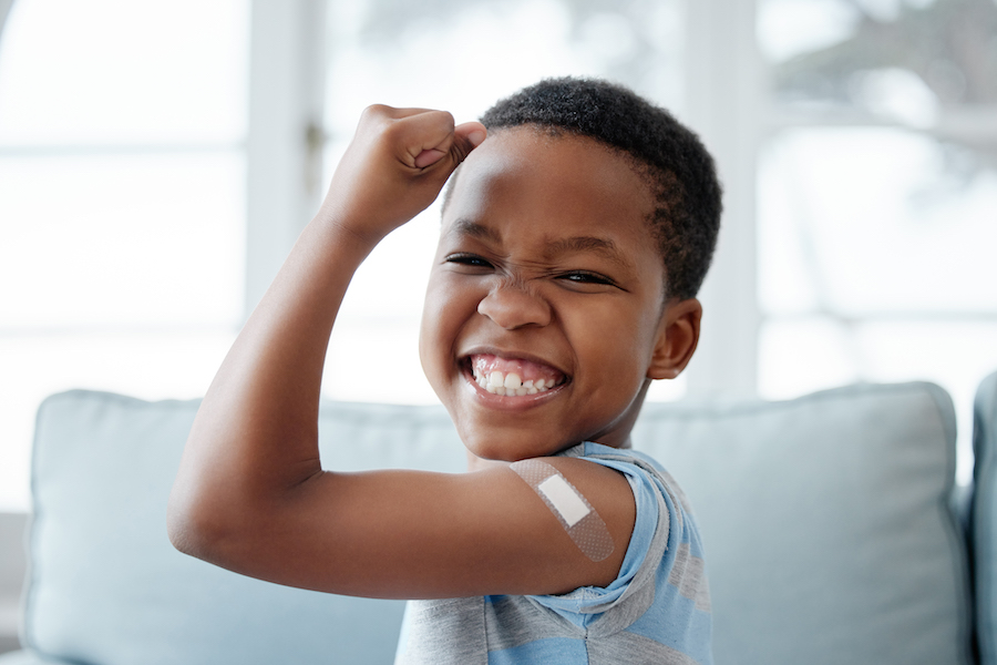 boy with band-aid giving a muscle arm to show strength